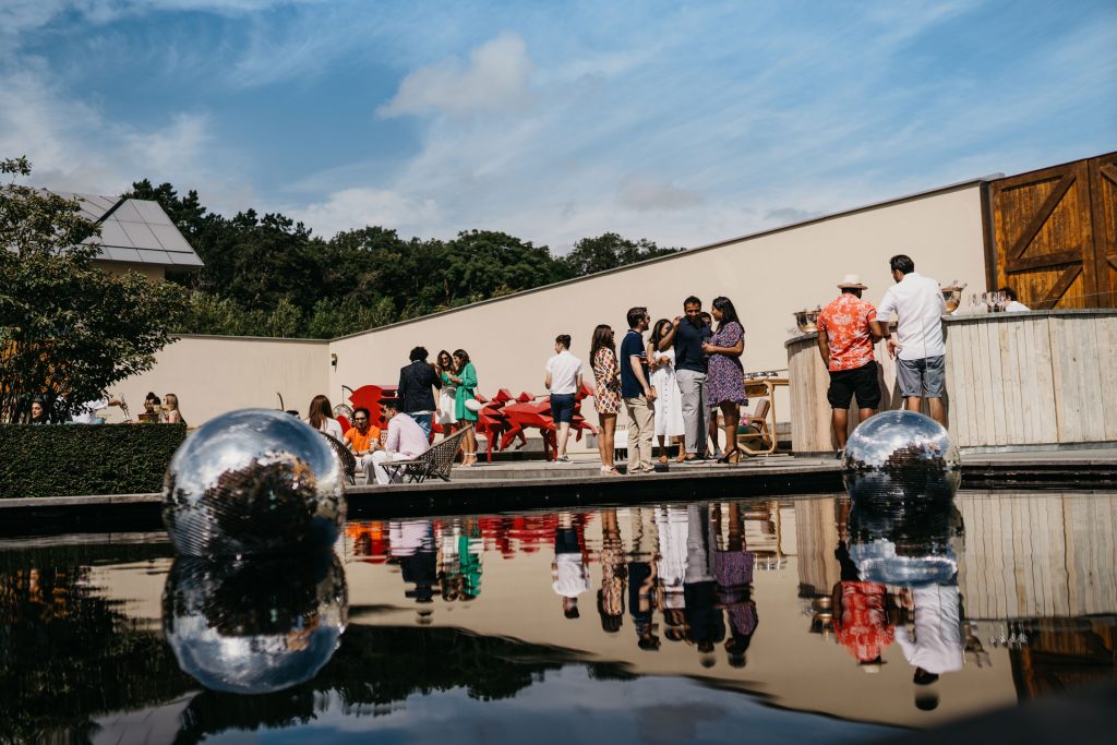 A group of people enjoying food and drink on a platform in front of a water feature.