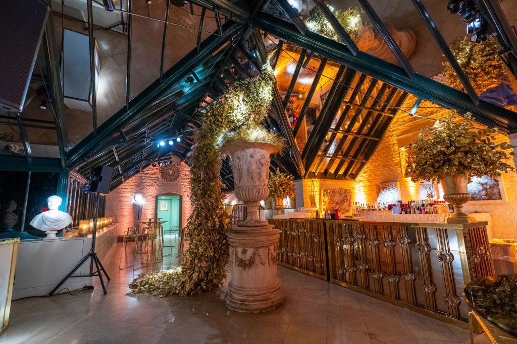 A gold bar and a gold peacock sculpture set on top of a stone urn.