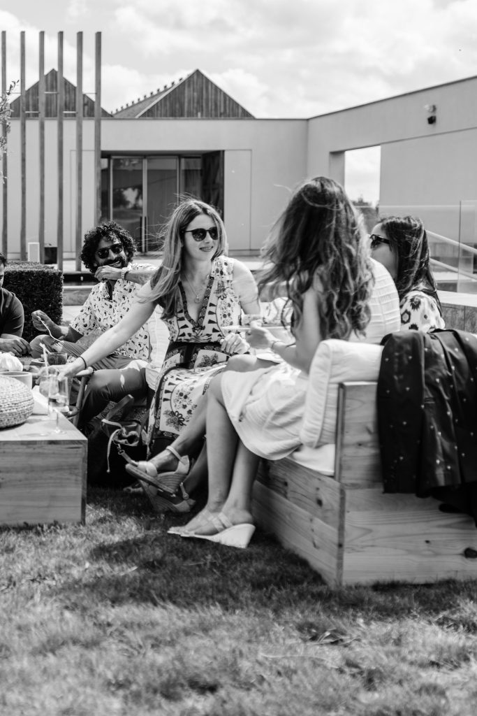 Black and white image of women chatting on wooden sofas