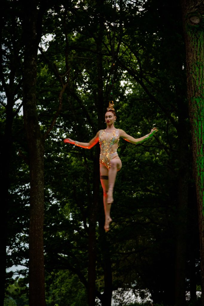 A hair aerialist suspended amongst the trees