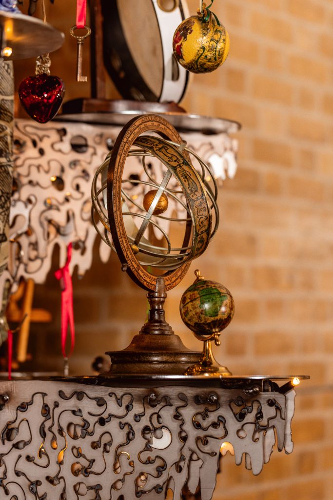 A zodiac planetarium and small desk globe on a metal shelf