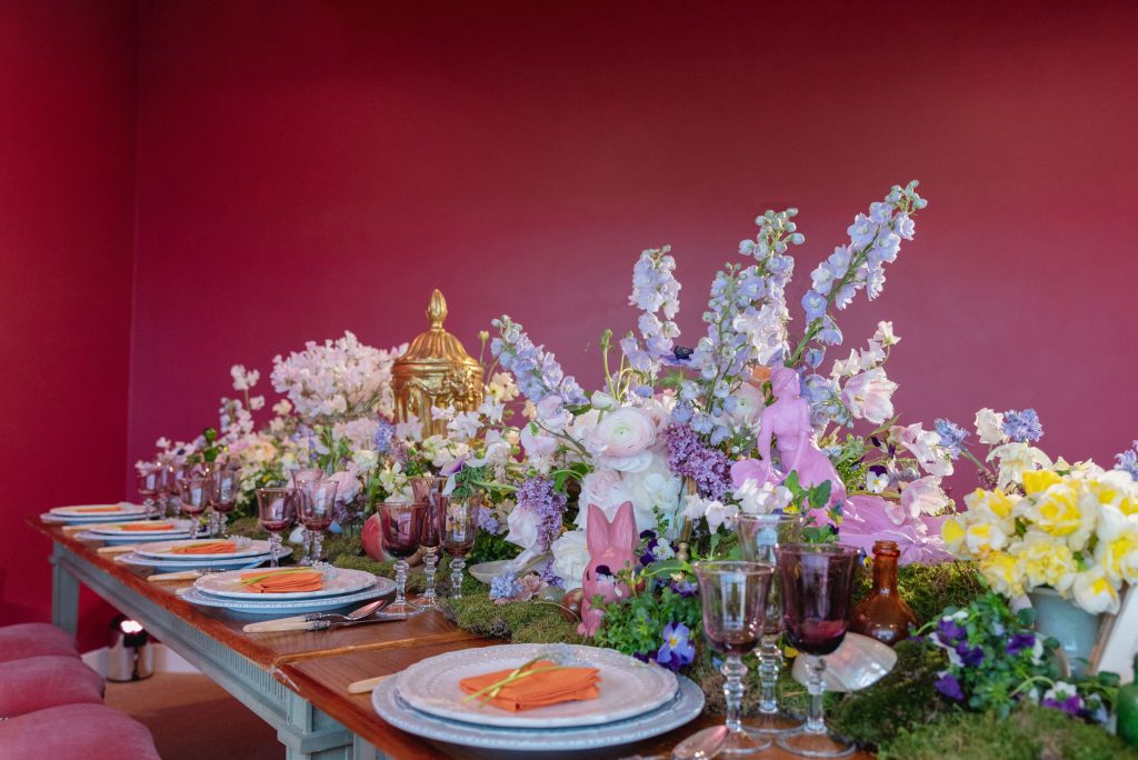 Spring flowers in pastel colours with blue china and plum coloured glassware.