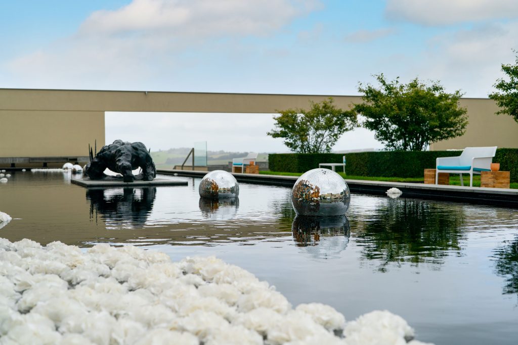 A water feature with floating white hydrangea heads, floating silver disco balls and a lookout over an horizon.
