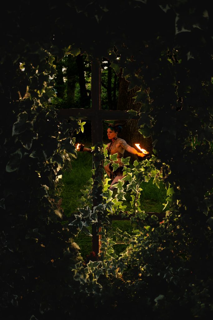 Fire performer seen through a window covered in ivy.